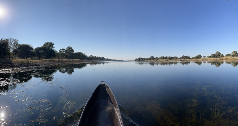 Canoe on a calm river with trees on the banks