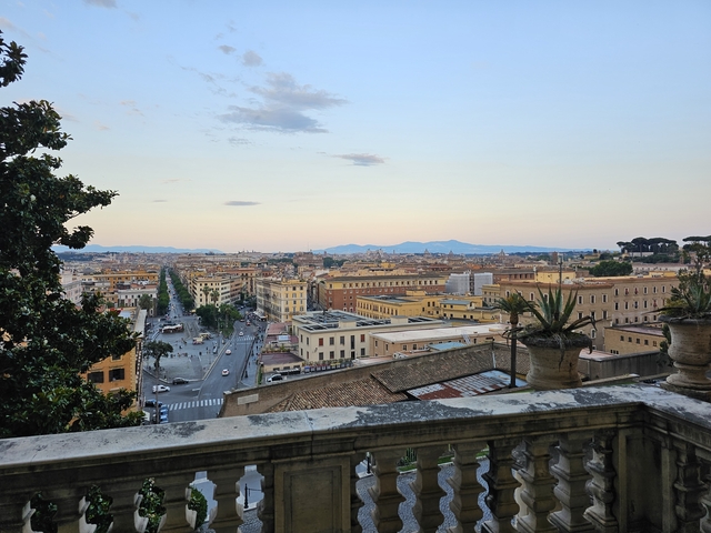 Panoramic cityscape view of Rome with mountains in the distance.