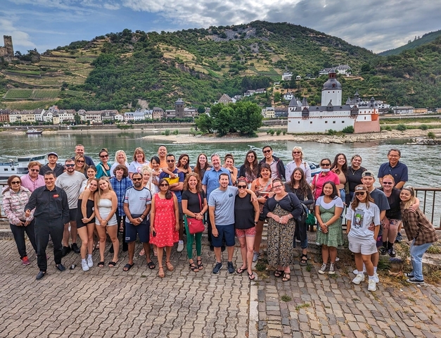       Group of tourists posing by a river with scenic view.
  