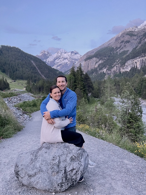 Couple embracing with a mountainous landscape and river.