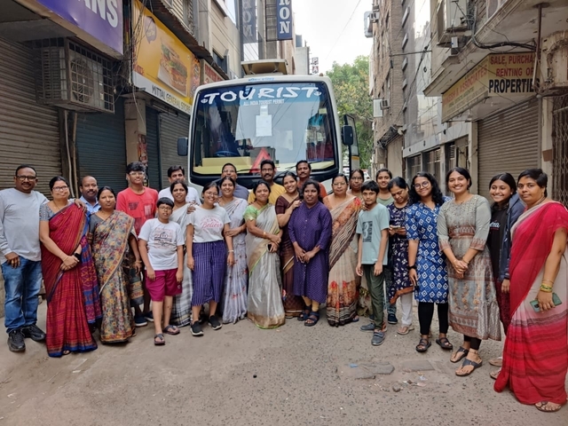 Group of people posing in front of a tour bus.