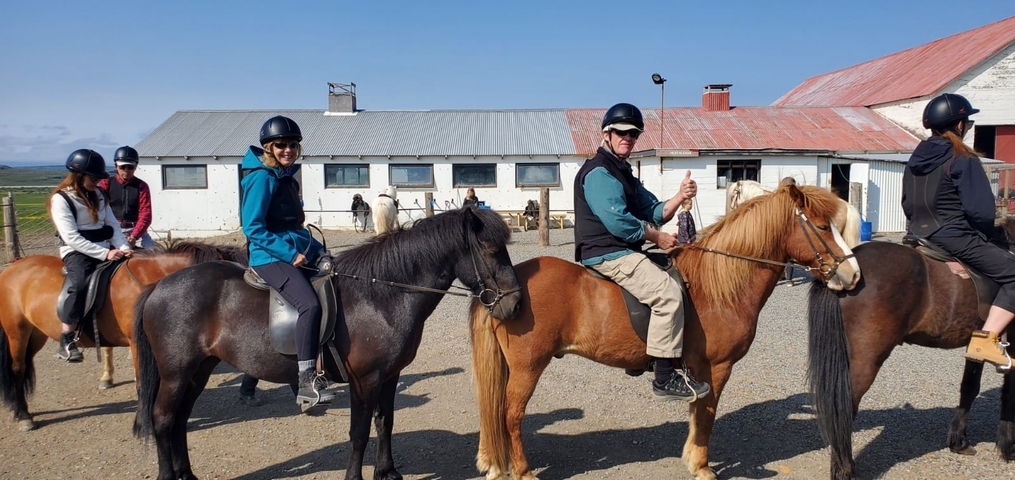 People riding Icelandic horses at a farm.