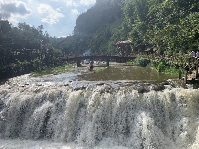 Waterfall with a scenic bridge and people around