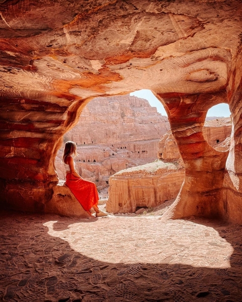 Woman sitting inside a natural rock formation with views of Petra