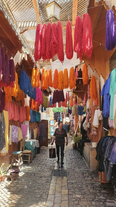 Colorful market with dyed yarns hanging in a narrow street.