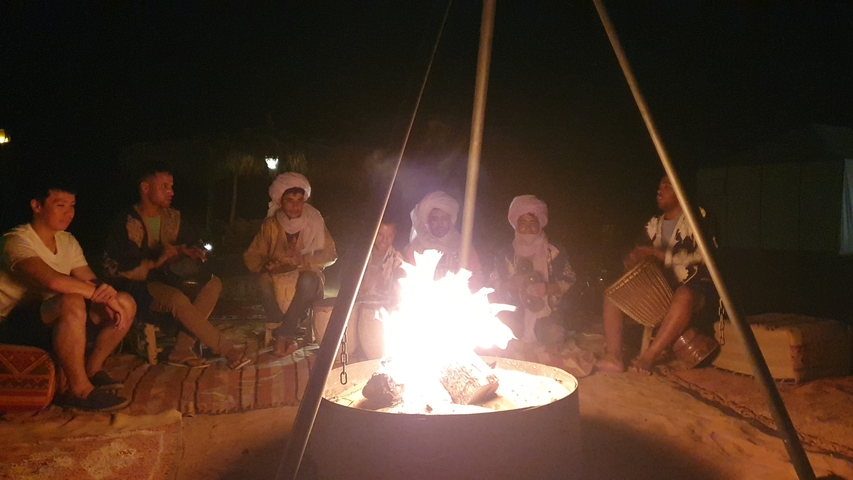       Group of people gathered around a campfire at night.
  