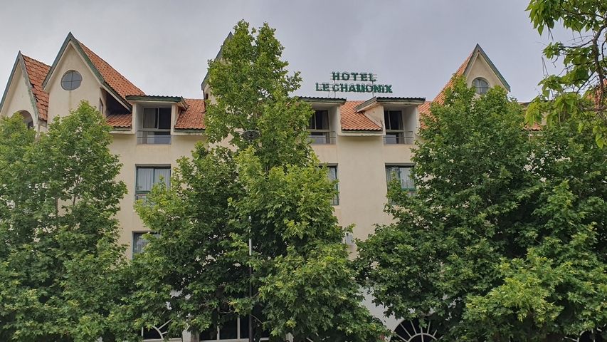       Hotel facade with trees in the foreground.
  