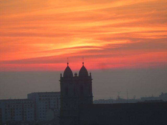       Silhouette of church towers against a vibrant sunset sky.
  