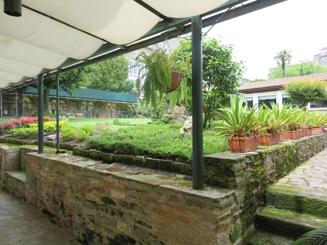       A garden courtyard with plants and stone walls.
  