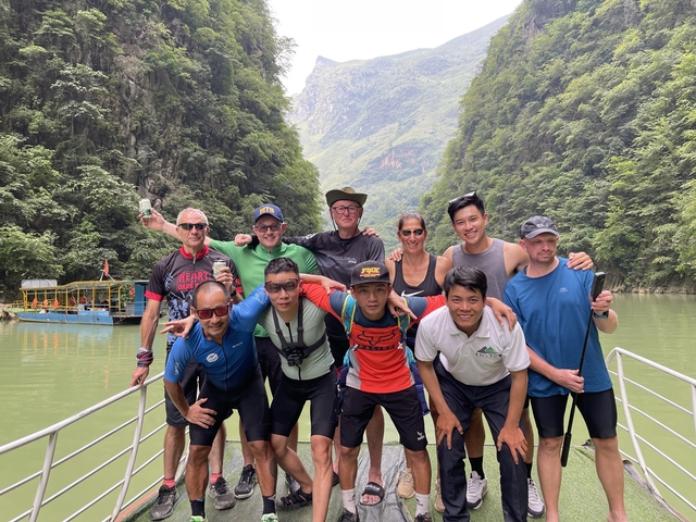       Group posing on a boat with a scenic river canyon backdrop.
  