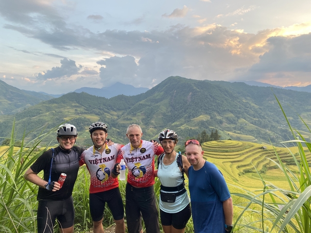       Group of cyclists with scenic terraced hills.
  