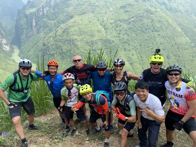 Group of cyclists posing with a scenic mountainous backdrop.