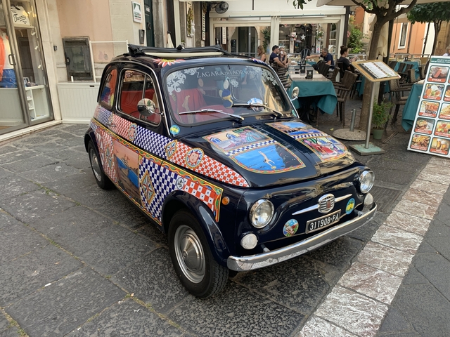       Colorful classic car parked on a cobblestone street.
  