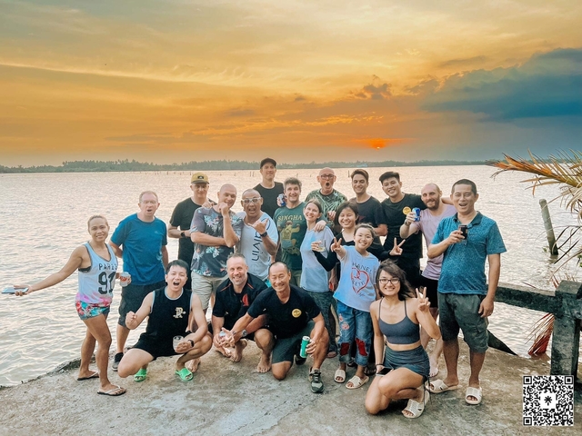 Large group of people enjoying a sunset by a river.