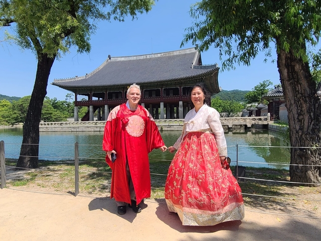 Couple wearing traditional Korean hanbok in front of a historic palace.