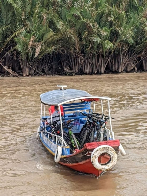 Bicycles on a small boat in a river near dense vegetation.