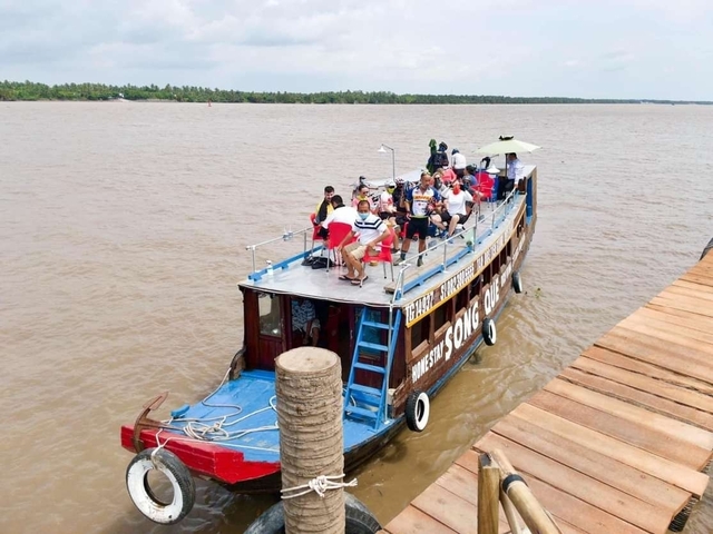 People gathered on a large riverboat near a dock.