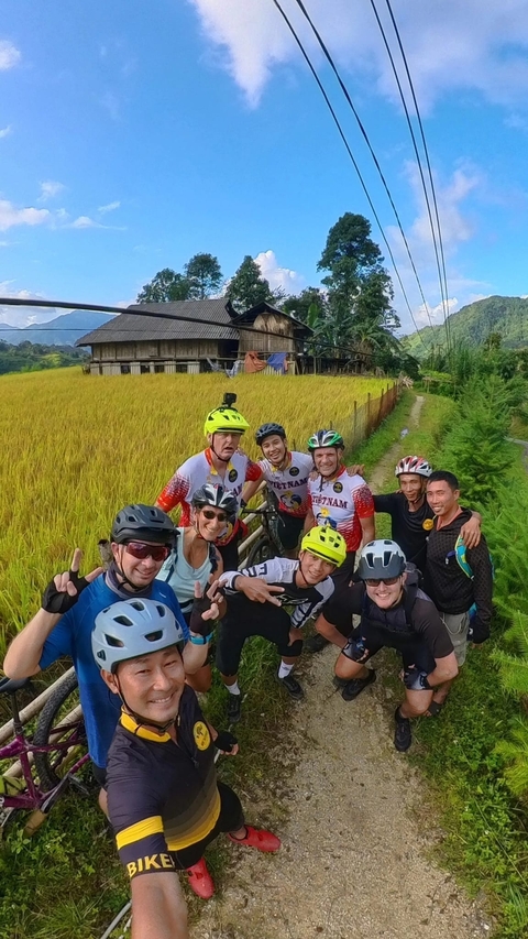 Group of cyclists posing in a lush rice field.