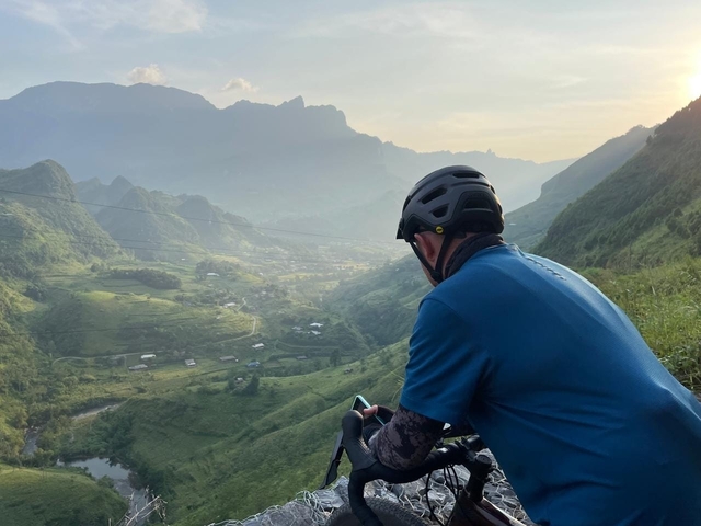 Cyclist overlooking a mountainous valley at sunrise.