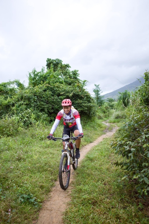 Person cycling through a lush trail.