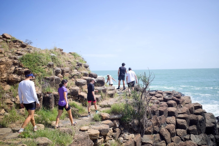 People walking along a rocky shore.