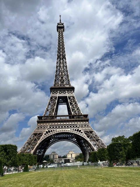      The Eiffel Tower in Paris against a cloudy blue sky.
  