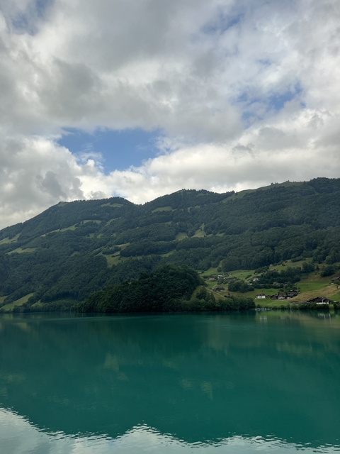       A hilly landscape with lush green forests and a serene lake.
  