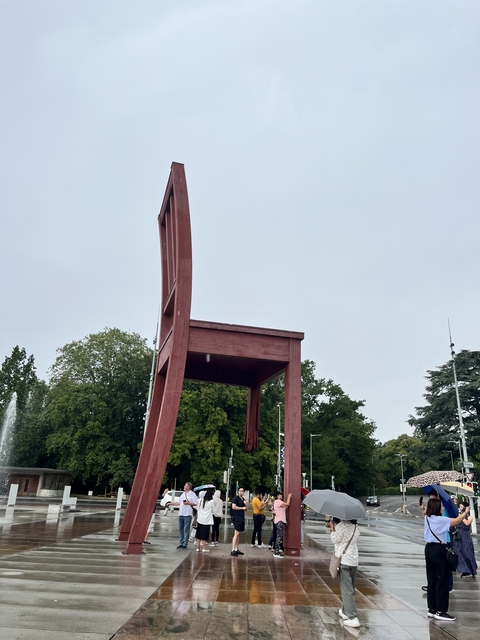       A large wooden chair sculpture in a park area.
  
