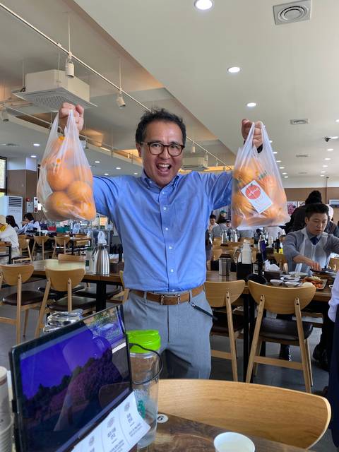 A person holding bags of oranges in an indoor setting.