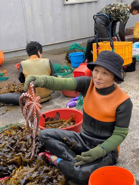 Female diver holding an octopus at a seafood market.