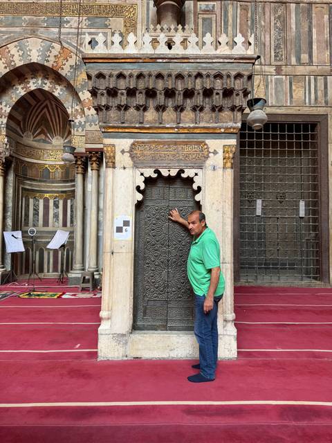 Person posing inside a historic mosque with intricate decor.