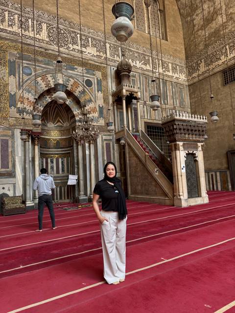       Tourist posing inside a mosque with detailed architecture.
  