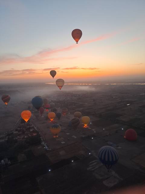 Hot air balloons flying over a landscape at sunrise.