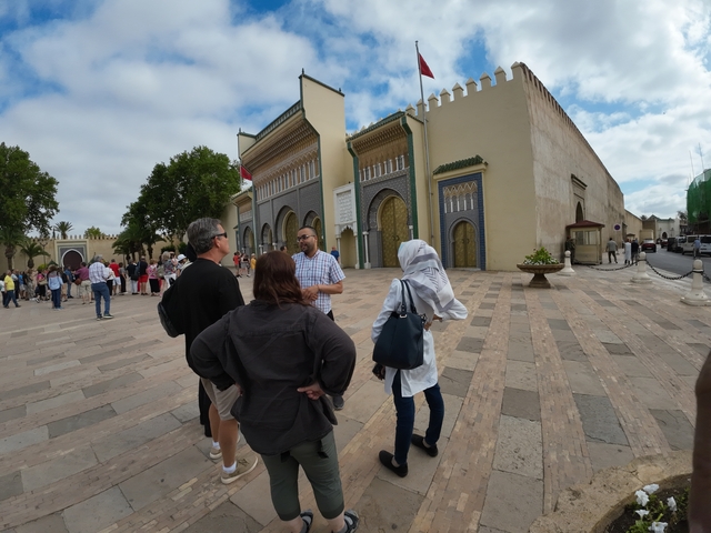      Tourists in front of a historical building with intricate doors.
  