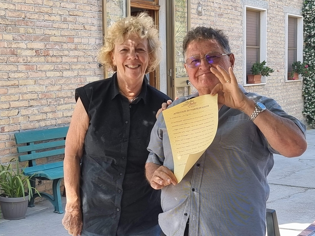 Two people smiling and holding a document.