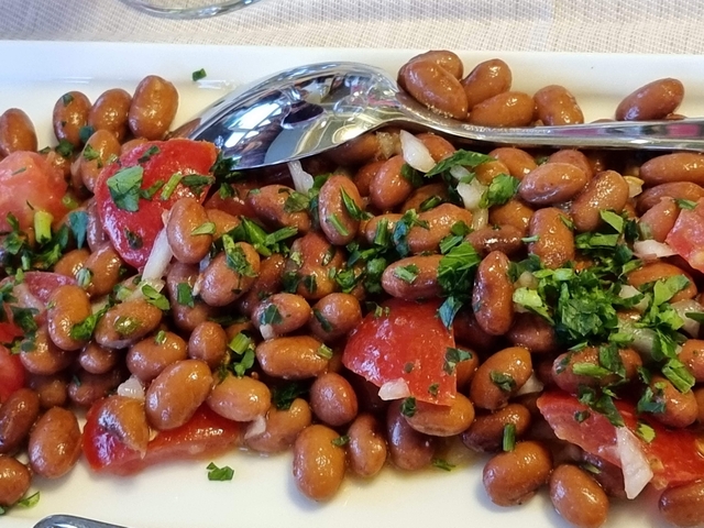 Close-up of bean salad with tomatoes and parsley.