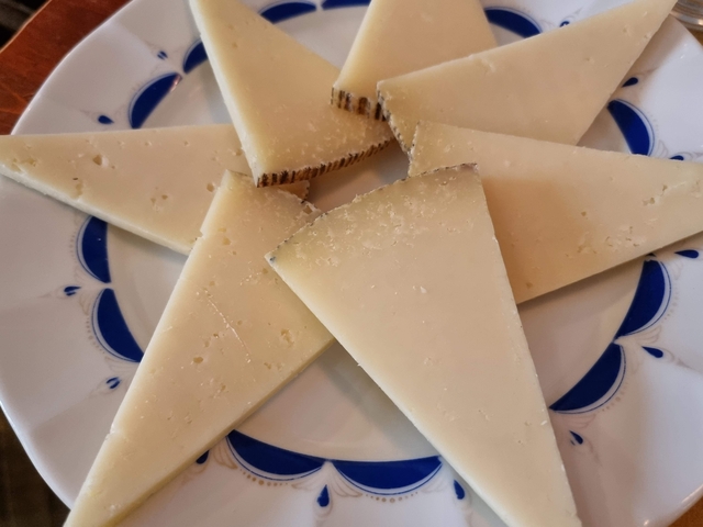 Slices of hard cheese arranged on a decorative plate.