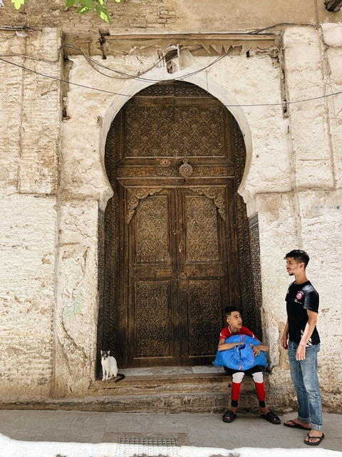 Two young men by an ornate wooden door