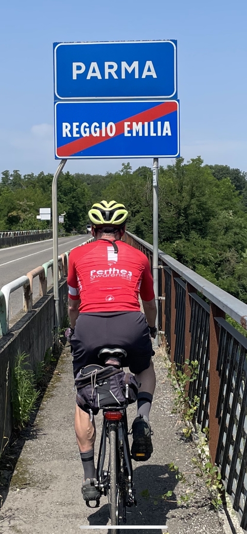 Cyclist in a red jersey riding on a bridge