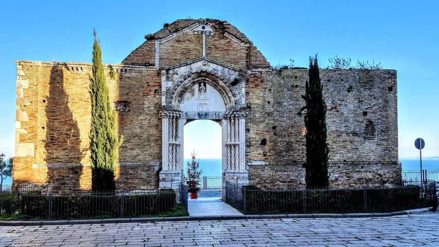 Ancient stone structure with an archway and trees