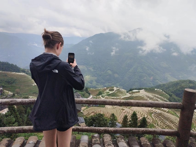 Person taking a photo of rice terraces with mountains