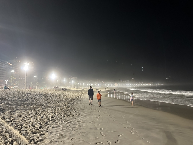 Family walking along a beach at night.