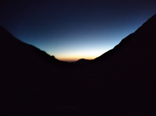 Silhouette of mountains at sunset with a gradient sky.