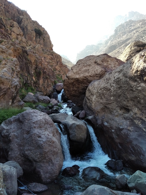Flowing stream through rocky terrain with mountains in the background.