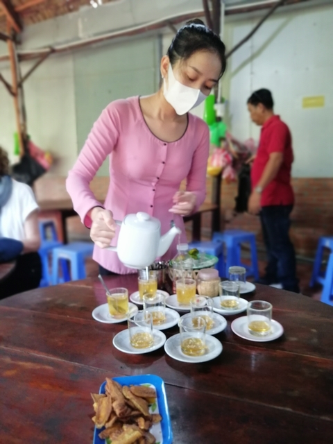       Blurred image of a person pouring tea in a cafe.
  