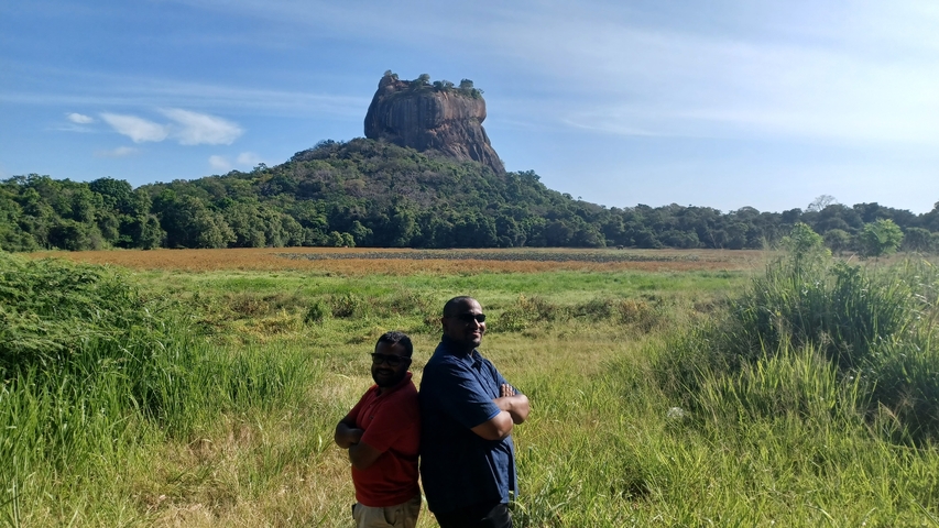 Two men posing in front of Sigiriya Rock Fortress.