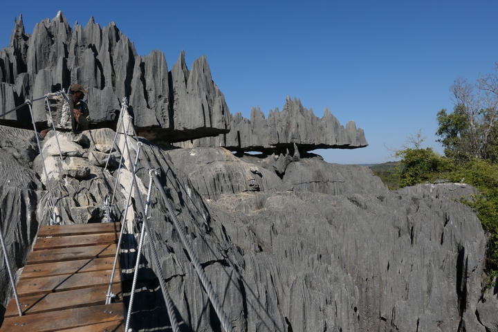       Hiker crossing a bridge over striking rock formations.
  