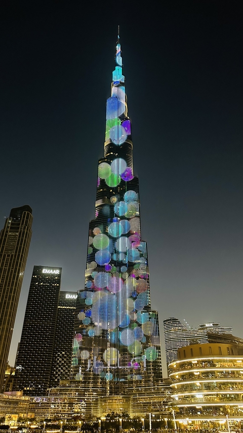 Tall skyscraper with colored lights in the night sky.