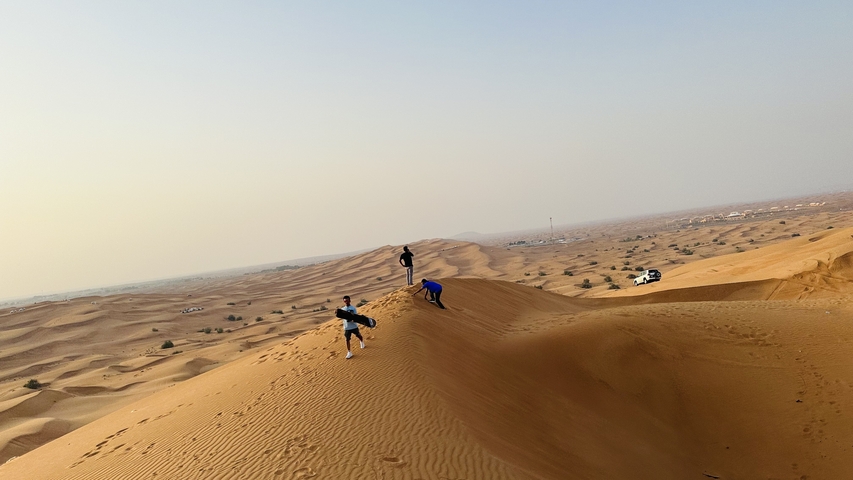 People walking on sand dunes in a desert landscape.