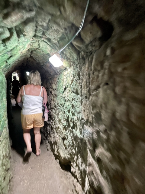       Person walking through a narrow stone tunnel.
  